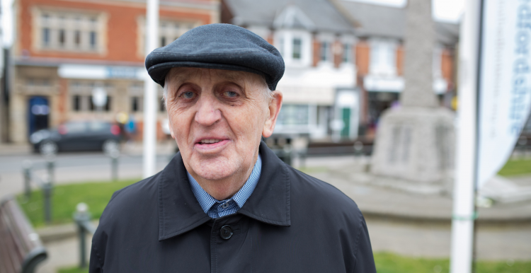 Elderly man wearing a cap standing outdoors