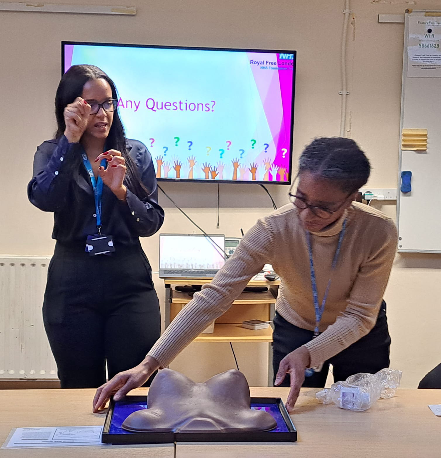 Two female health promotion workers giving a presentation on breast screening