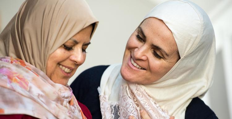Two muslim women posing smiling talking looking at each other