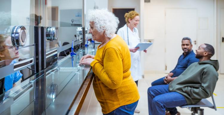 Senior woman talking to a receptionist with a doctor in the background