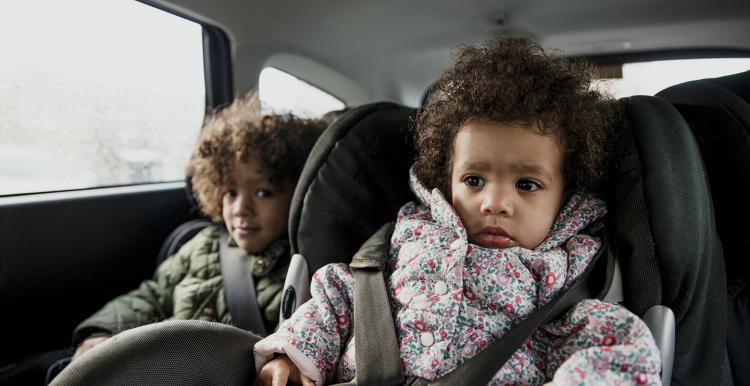 Two young children in the back of a car in car seats
