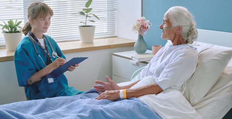 Elderly woman talking with young female doctor in hospital ward