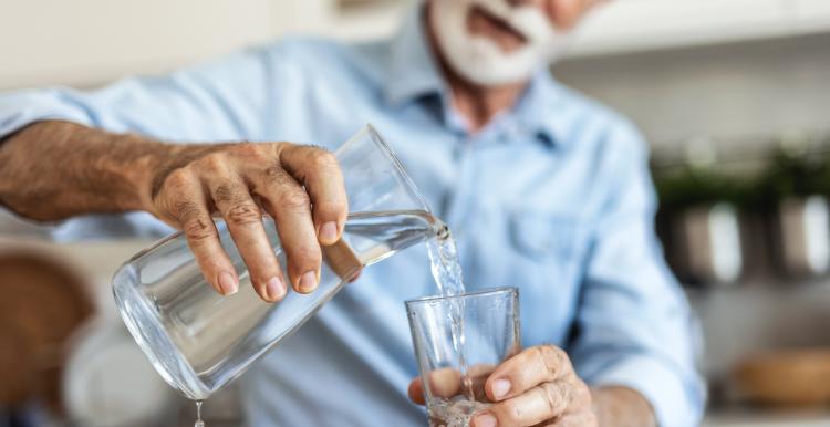 Man pouring water from cask into glass