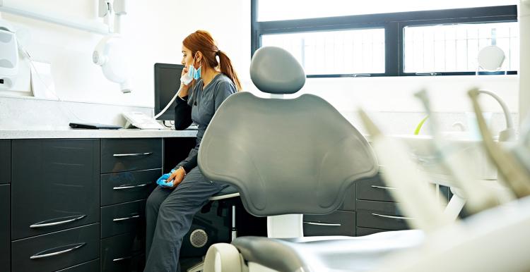 Female dentist sitting at her desk in medical room talking on telephone