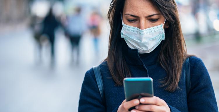 Woman wearing a facemask and looking at her smartphone