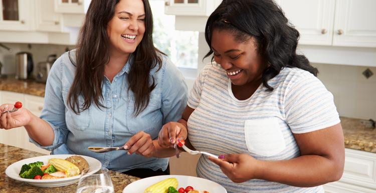 Two women laughing eating a healthy meal