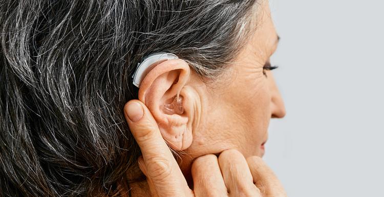 A woman's head in profile with a hearing aid visible