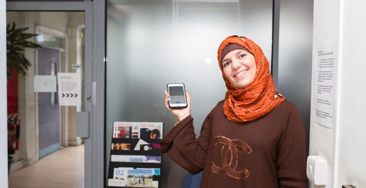 Smiling lady in a headscarf holding up a smartphone