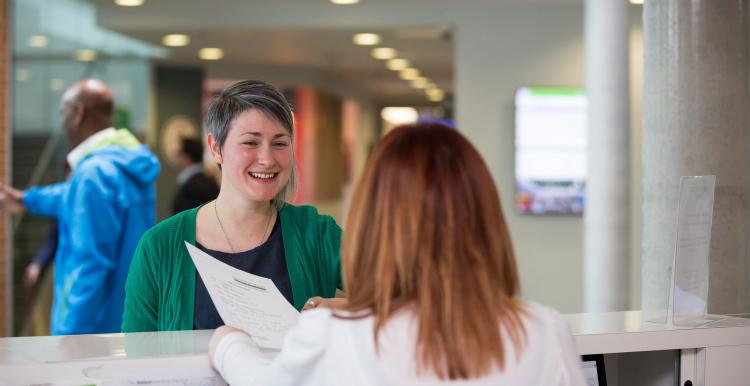 Young woman in a waiting area talking to a receptionist