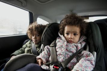 Two young children in the back of a car in car seats