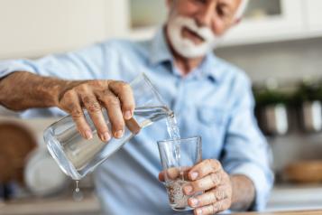 Man pouring water from cask into glass