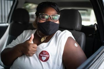 Portrait of a happy woman in a car with a 'get vaccinated' sticker 