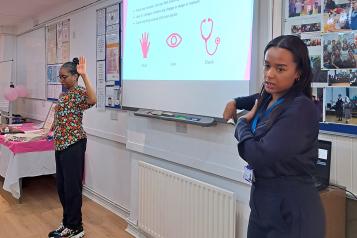 Two women delivering a breast cancer awareness session in a community setting