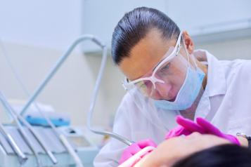 Experienced dentist treats teeth in patient