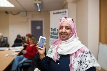 Woman in headscarf holding up a smartphone