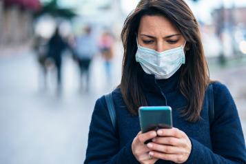 Woman wearing a facemask and looking at her smartphone