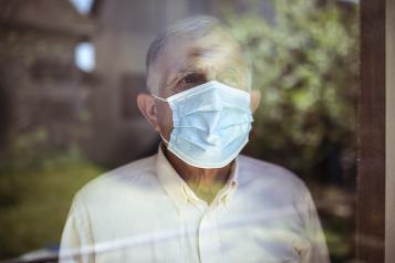 Man wearing a face mask looking out of a window