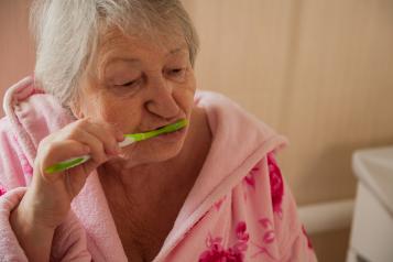 Elderly woman brushing her teeth