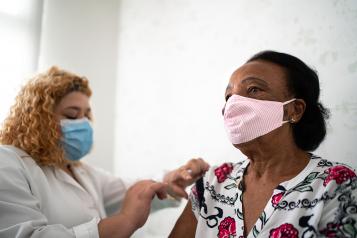 Black woman in a facemask having her flu jab