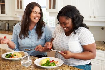 Two women laughing eating a healthy meal