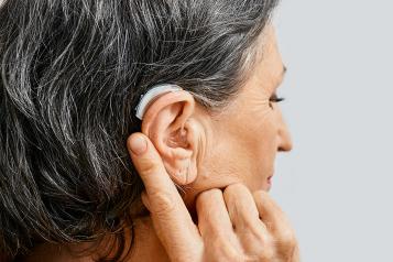 A woman's head in profile with a hearing aid visible