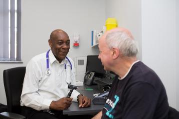 Doctor holding otoscope and sitting with a patient