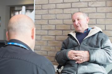 Older man in a hospital setting talking with a doctor