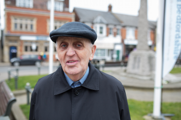 Elderly man wearing a cap standing outdoors
