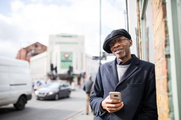 Smiling man standing next to a busy road