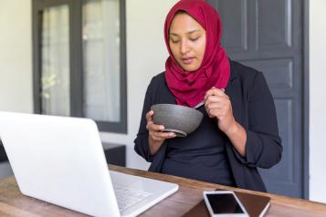 Muslim woman with a laptop eating healthily
