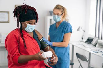 Woman getting her blood pressure measured during a checkup with a nurse, before she is getting a COVID-19 vaccine