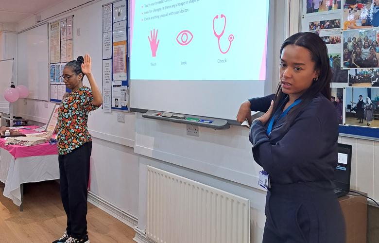 Two women delivering a breast cancer awareness session in a community setting