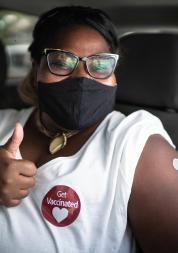 Portrait of a happy woman in a car with a 'get vaccinated' sticker 